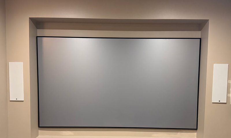 Projection screen in a wall recess with in-wall speakers either side