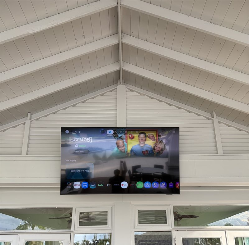 TV mounted high on a white vaulted gable above glass doors