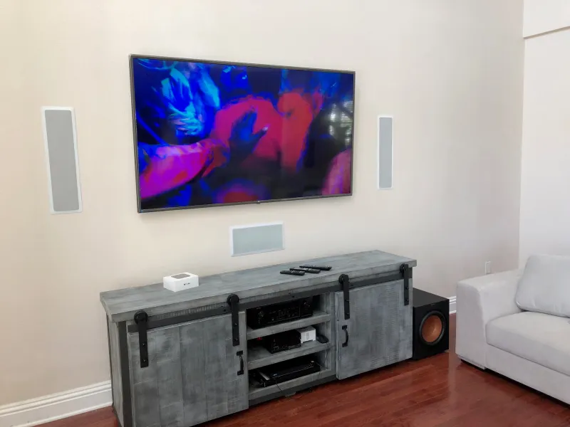 TV with in-wall speakers above a media console