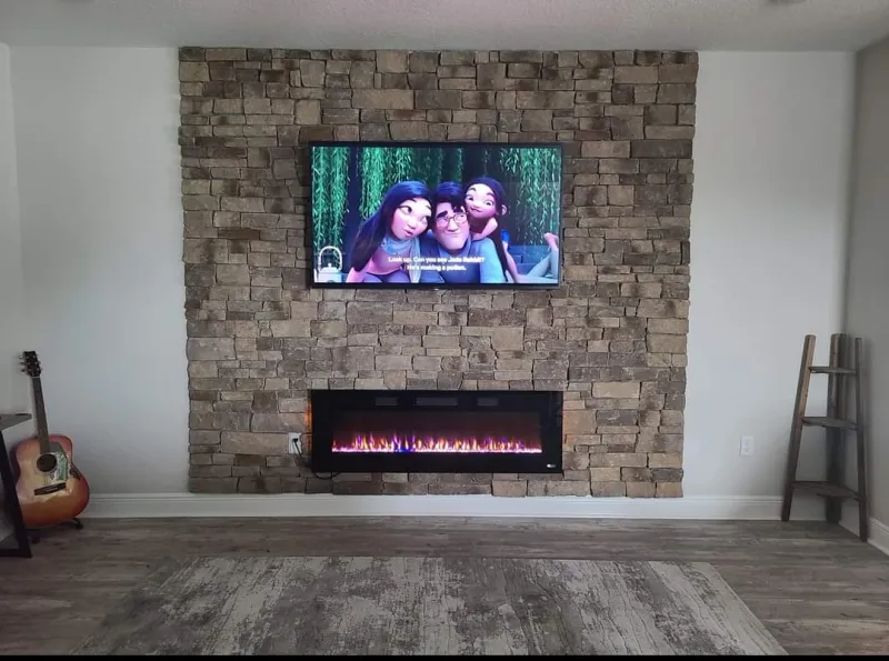 TV on a stacked-stone wall above an electric fireplace