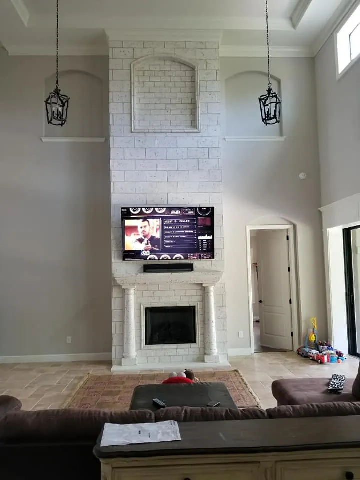 TV above a tall white brick fireplace