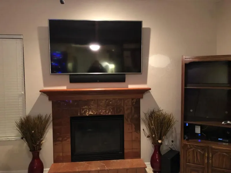 TV above a fireplace with a wood mantel