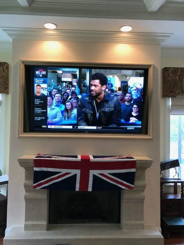 TV framed above a mantel, with a Union Jack cushion
