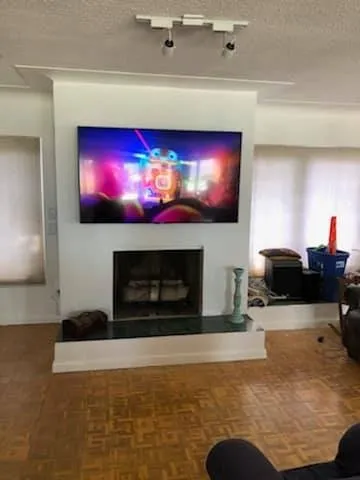 TV above a fireplace with a white mantel