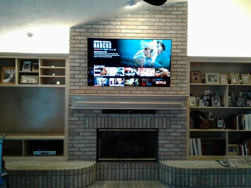 TV over a brick fireplace between built-in shelves